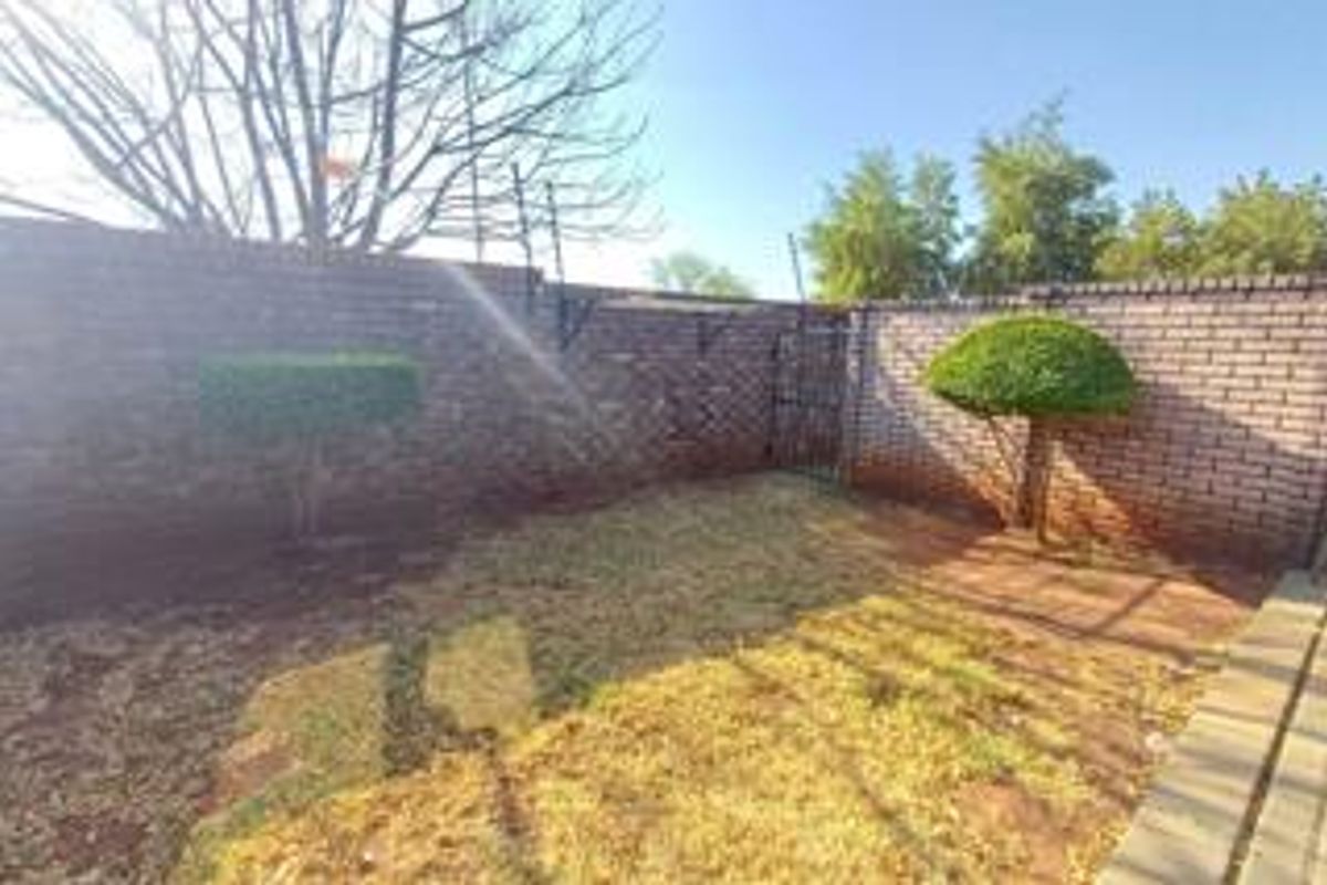 A private rear garden area featuring brick boundary walls with security spikes and a small metal access gate.