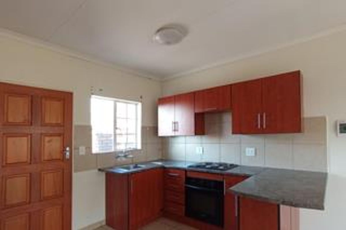 A functional kitchen featuring wood-finish cabinetry, laminate countertops, a built-in oven, gas hob, and a tiled backsplash.