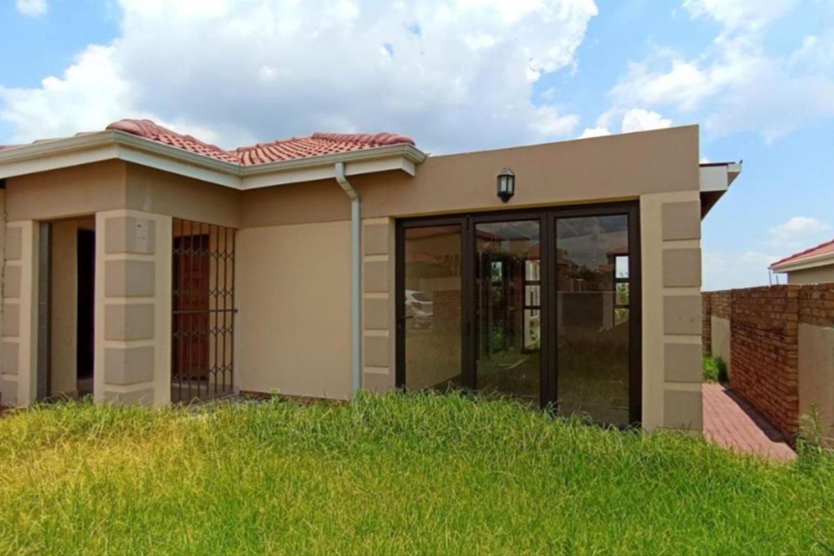 Rear view of the property featuring a paved walkway, sliding glass doors, and a private garden area.