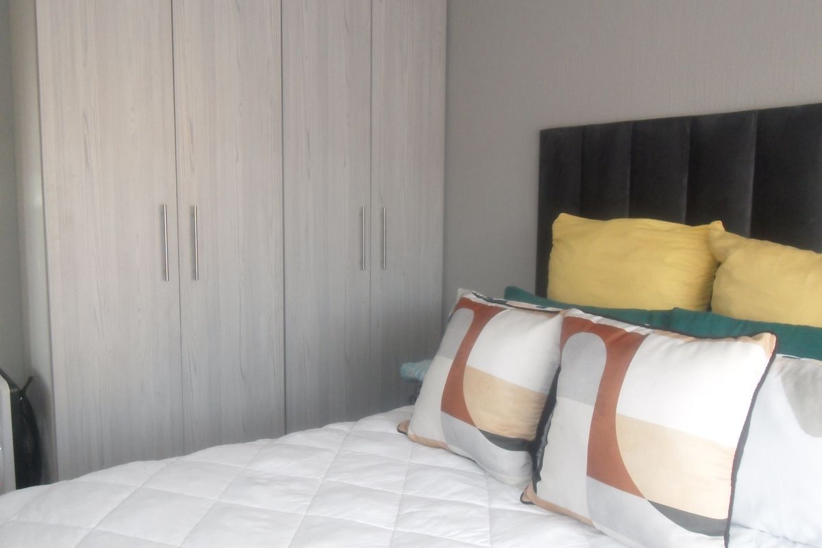 A bedroom featuring built-in light wood-grain cabinetry providing ample storage space.