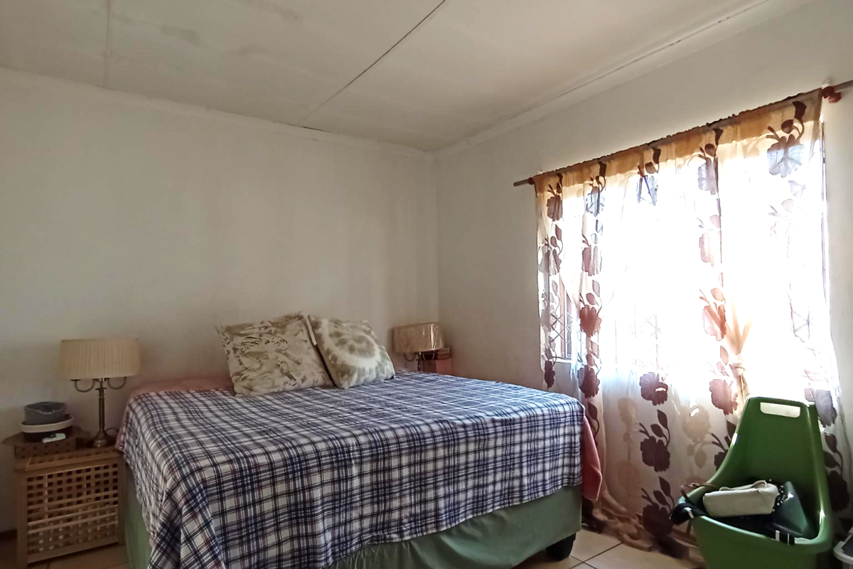 A bedroom featuring a window with curtain rod and tiled flooring, requiring cosmetic updates to improve the overall aesthetic.