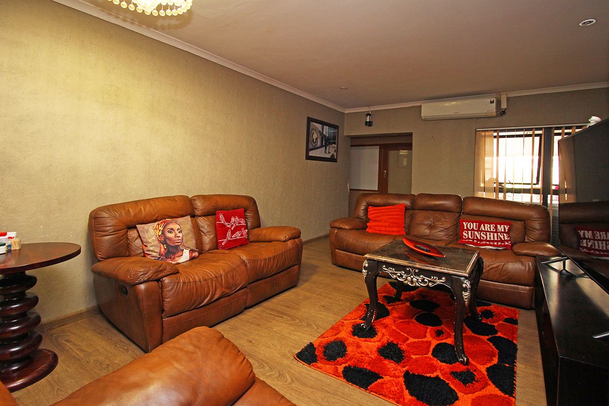 A comfortable living room featuring wood-look flooring, recessed downlighting, and a wall-mounted air conditioning unit.