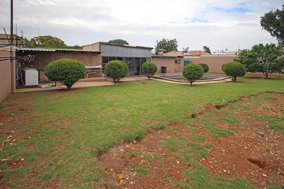 Spacious rear garden featuring a swimming pool, paved patio area, and established landscaping, offering potential for outdoor entertainment and recreation.