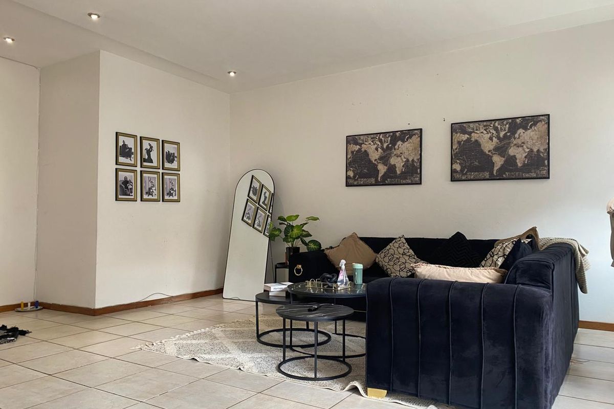 A spacious living room featuring neutral floor tiles, recessed ceiling lighting, and a clean, open layout suitable for comfortable seating arrangements.