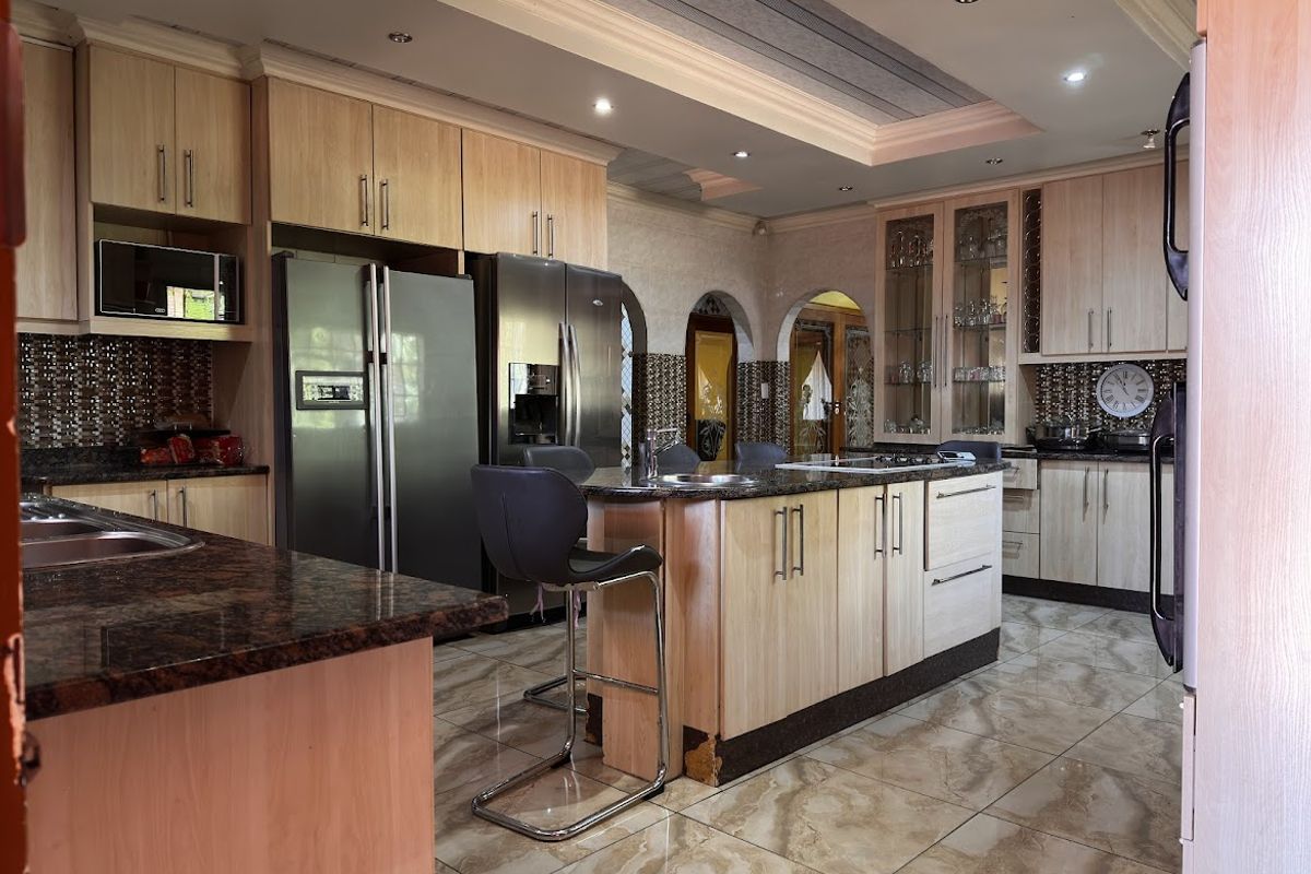 Spacious kitchen featuring light wood cabinetry, granite countertops, a central island with a prep sink, and tiled flooring with recessed ceiling lighting.