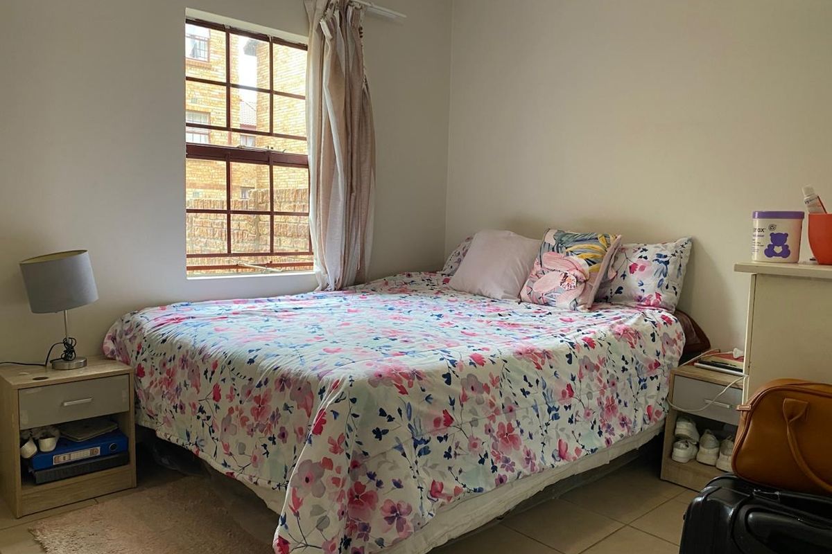 A functional bedroom featuring tiled flooring, a window with natural light, and neutral wall finishes, providing a comfortable space for rest.