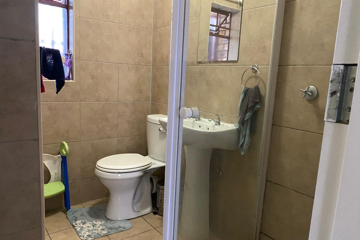 A functional bathroom featuring a pedestal basin, toilet, and tiled walls, providing essential amenities in a compact layout.