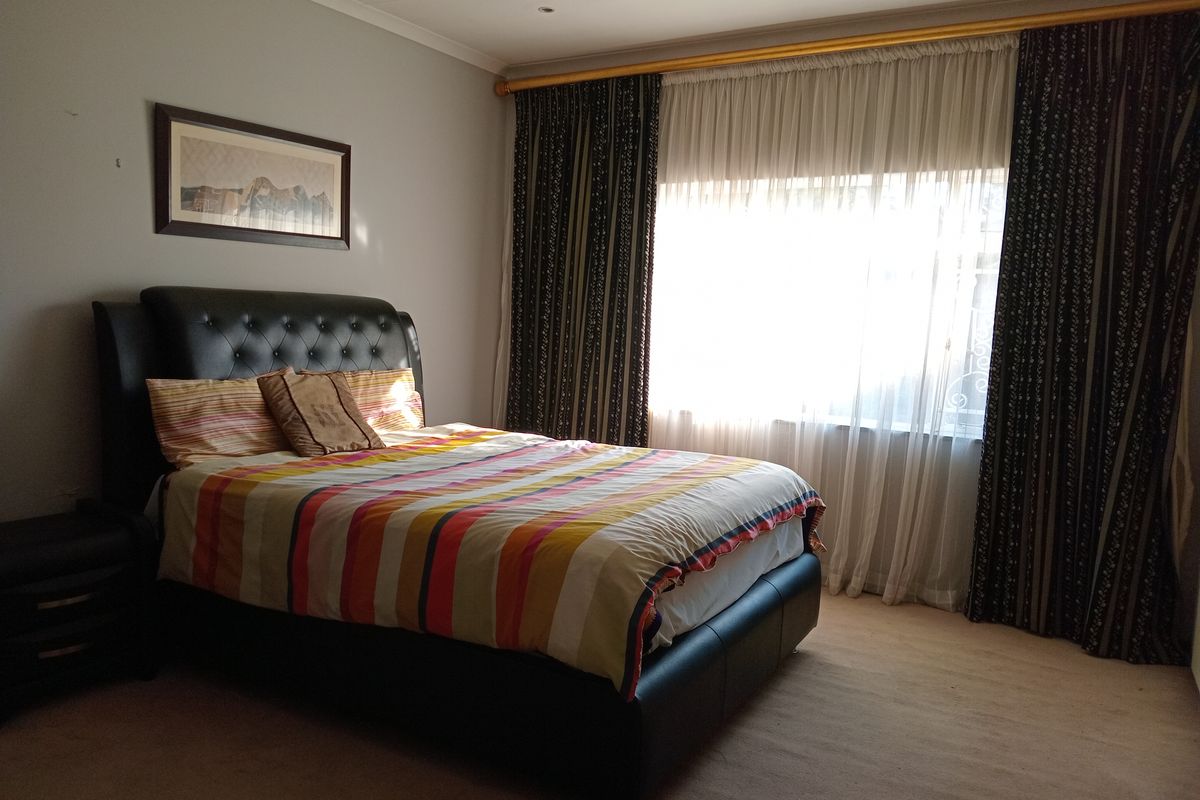 A well-proportioned bedroom featuring neutral carpeting, large window with curtain tracks, and recessed ceiling lighting.