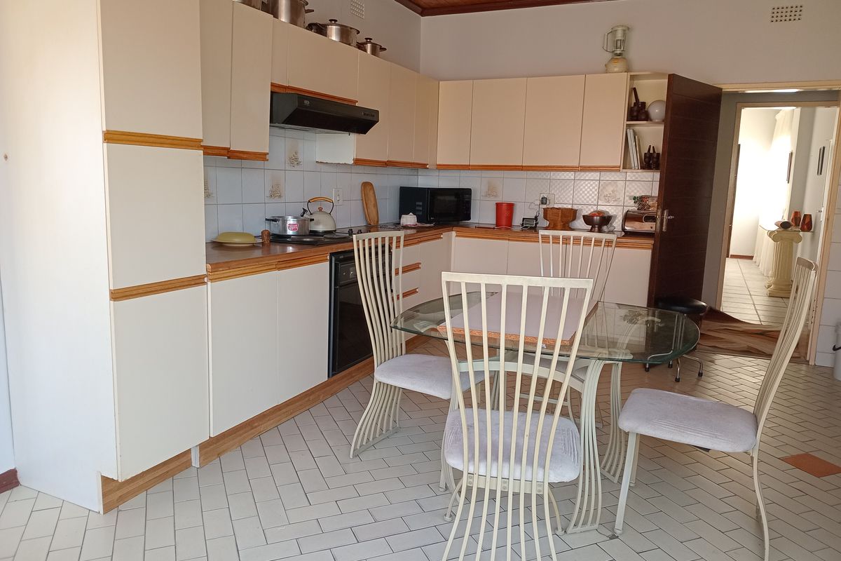 A functional kitchen featuring light-toned cabinetry, tiled splashbacks, and a tiled floor, with an integrated oven and extractor fan.