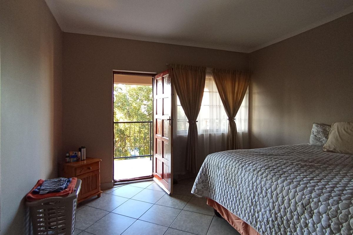 A bedroom featuring tiled flooring and direct access to an outdoor balcony through a wooden door.