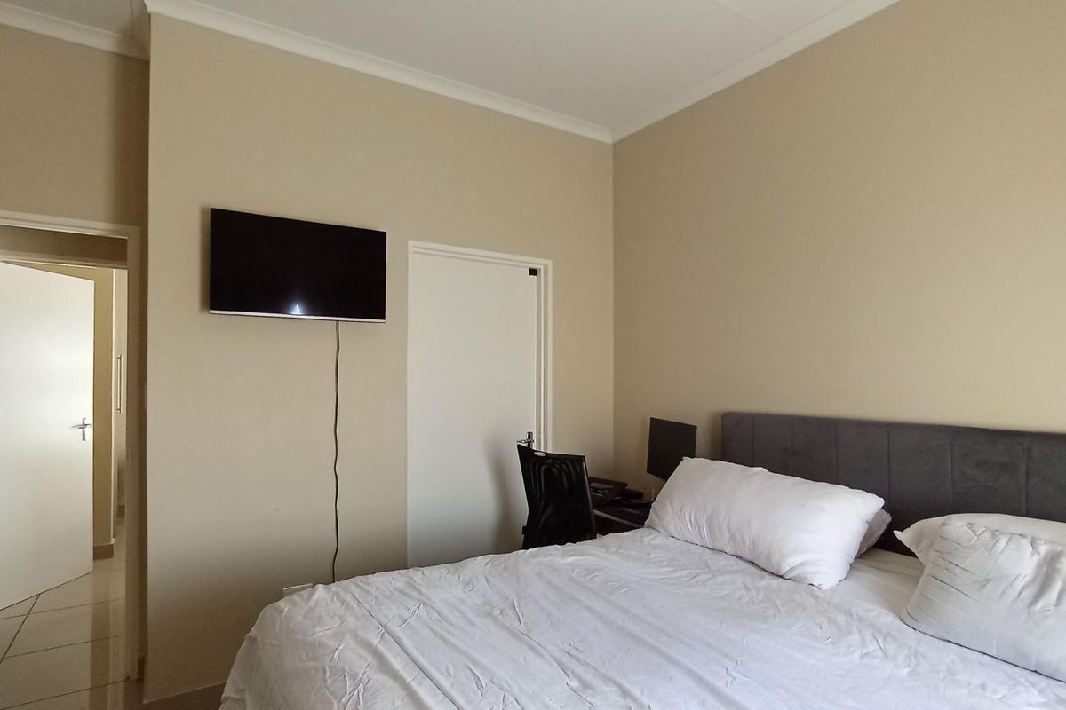 A bedroom featuring neutral wall tones, coved cornicing, and a doorway leading to an adjacent room with tiled flooring.
