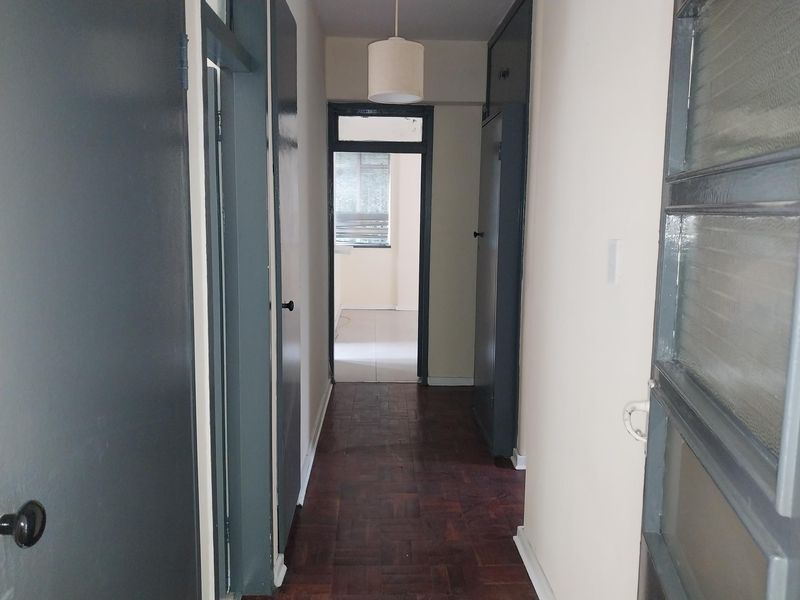 A functional hallway featuring classic parquet flooring, built-in storage cupboards, and multiple internal doors leading to adjacent rooms.