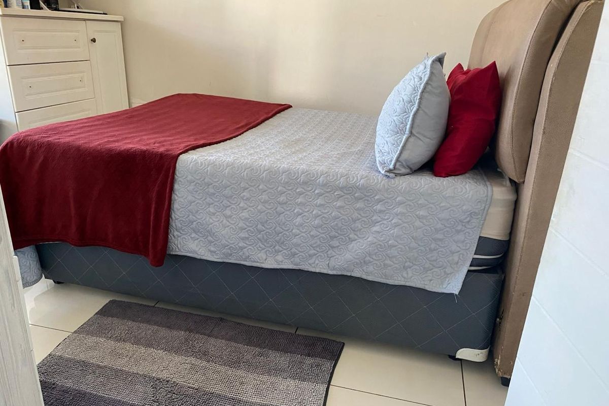 A bedroom featuring tiled flooring and neutral wall finishes, providing a functional and compact sleeping space.