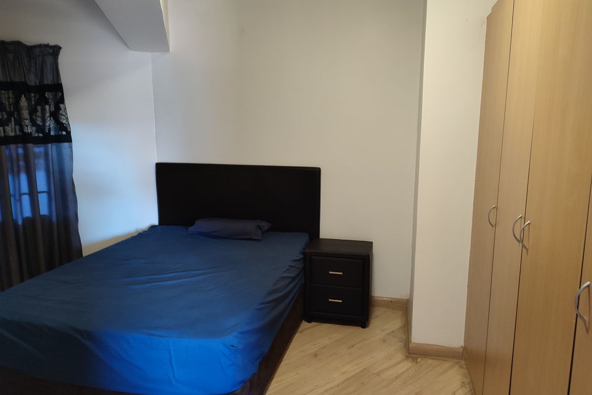A bedroom featuring light wood-look flooring and built-in wooden cabinetry, providing functional storage space.
