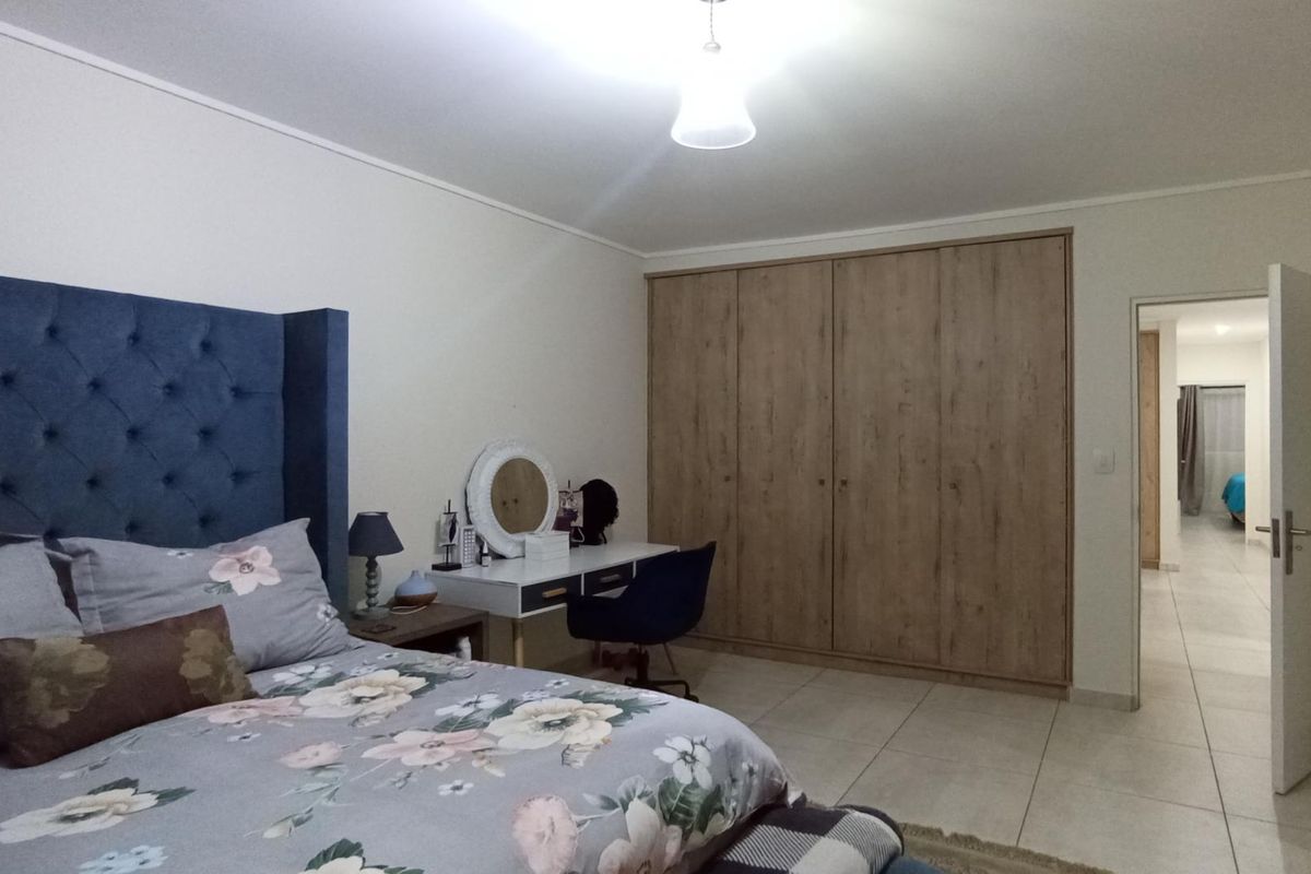 Spacious bedroom featuring large built-in wooden wardrobes, tiled flooring, and neutral wall finishes, providing a clean and functional living space.