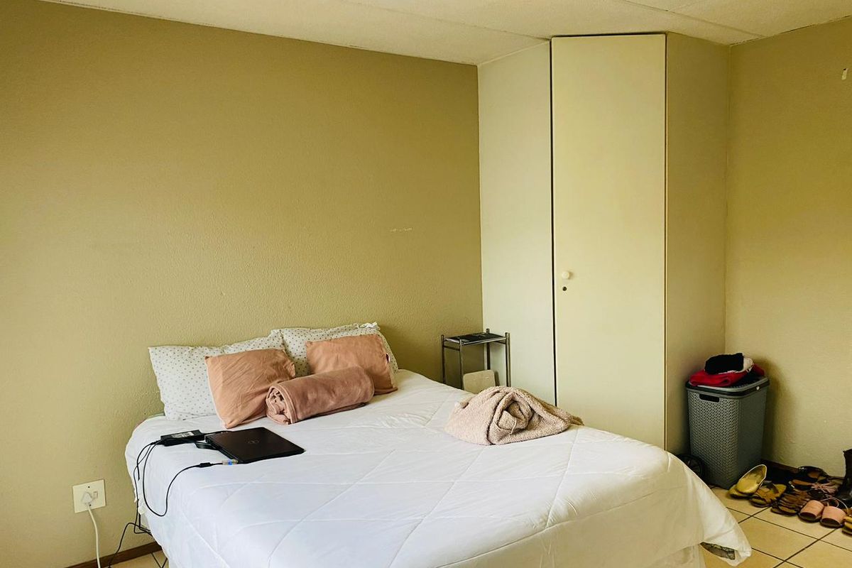 A bedroom featuring tiled flooring and a built-in wardrobe, requiring minor cosmetic updates to the walls and ceiling to improve its overall appeal.