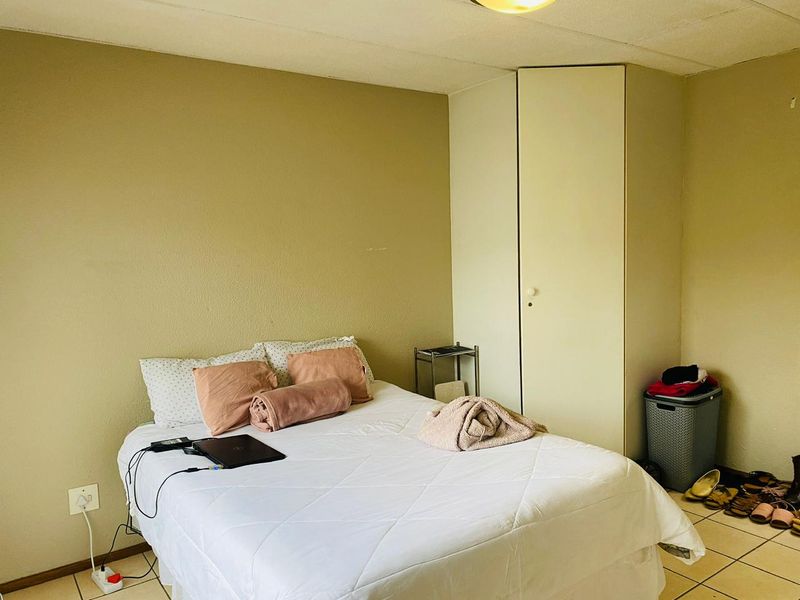 A bedroom featuring tiled flooring and a built-in wardrobe, requiring minor cosmetic updates to the walls and ceiling to improve its overall appeal.