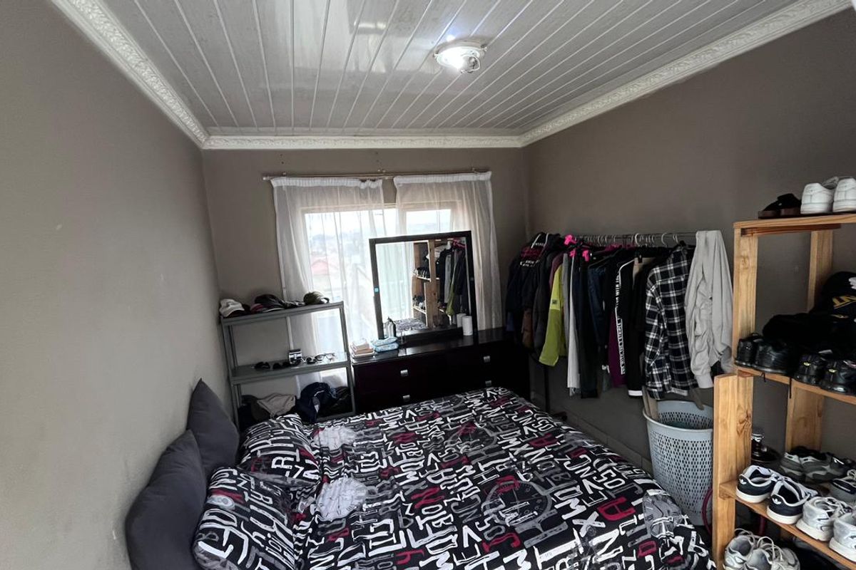 A functional bedroom featuring a glossy paneled ceiling with decorative cornice and a window providing natural light.
