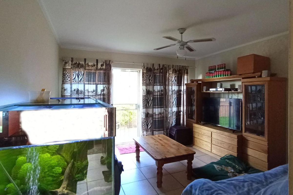 A living room featuring tiled flooring, a ceiling fan, and direct access to an outdoor balcony through a sliding glass door.
