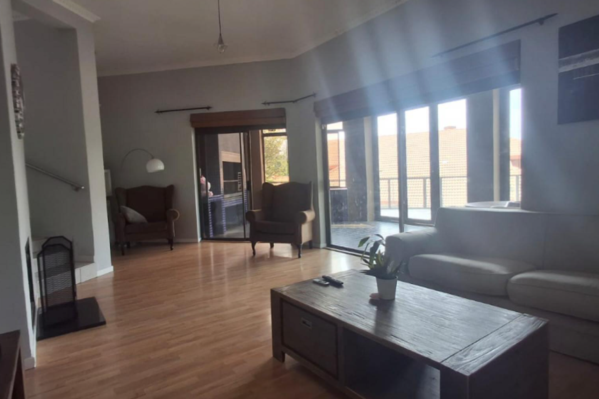 Spacious living room featuring laminate flooring, a fireplace hearth, and large sliding glass doors providing access to an outdoor patio area.
