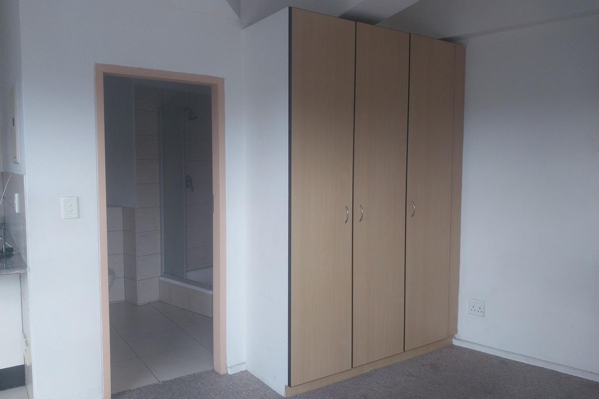 A bedroom featuring built-in wooden cabinetry and direct access to an en-suite bathroom with tiled flooring.