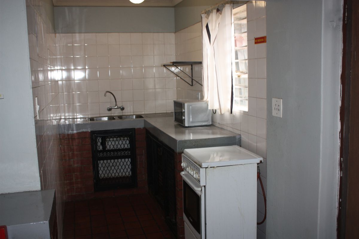 A functional kitchen area featuring tiled walls, a double sink, and a freestanding stove, offering a practical layout for meal preparation.