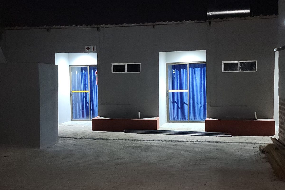 Night view of a lodge exterior featuring two guest room entrances with sliding glass doors and paved courtyard area.