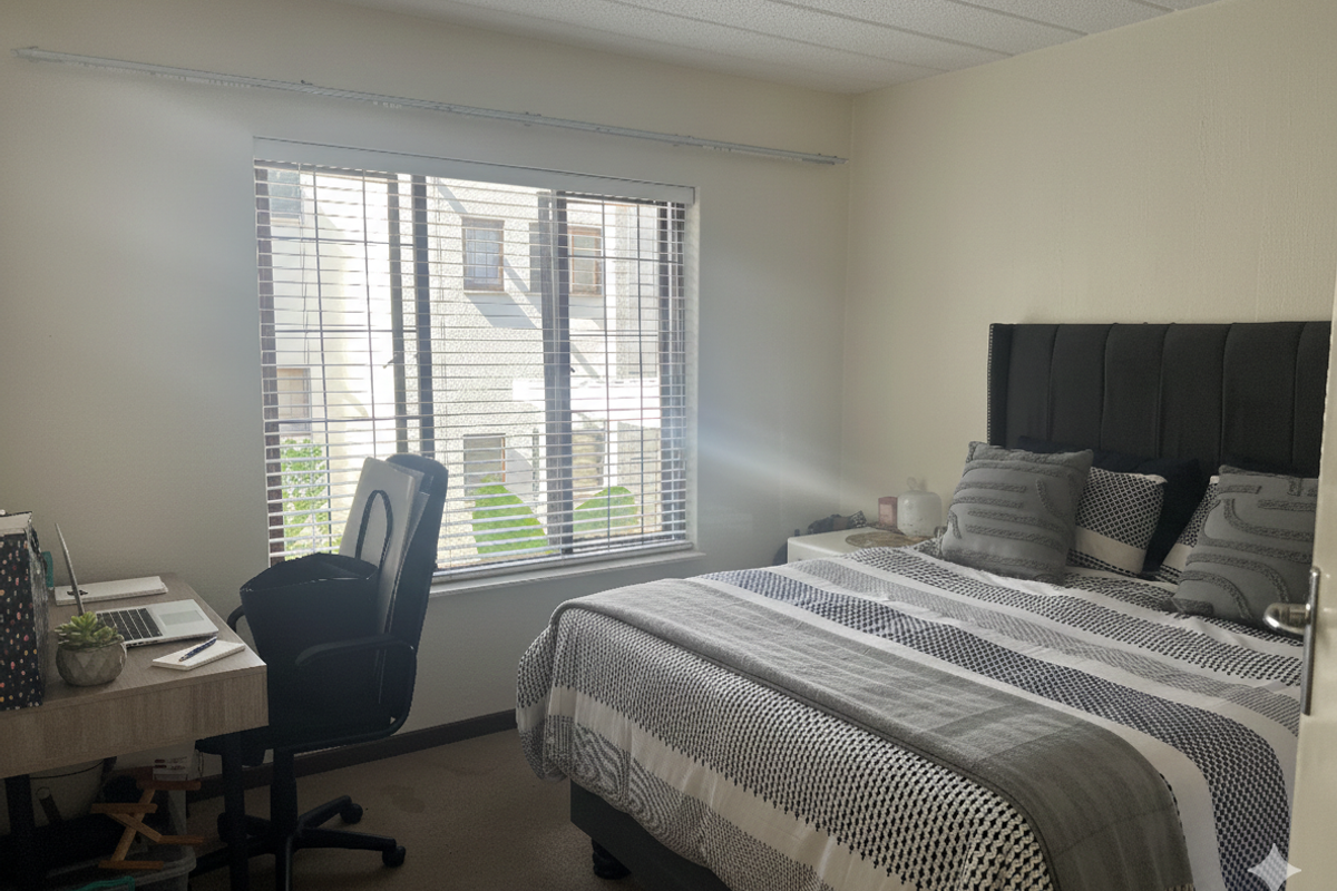 A functional bedroom featuring carpeted flooring, a textured ceiling, and venetian blinds allowing natural light into the space.