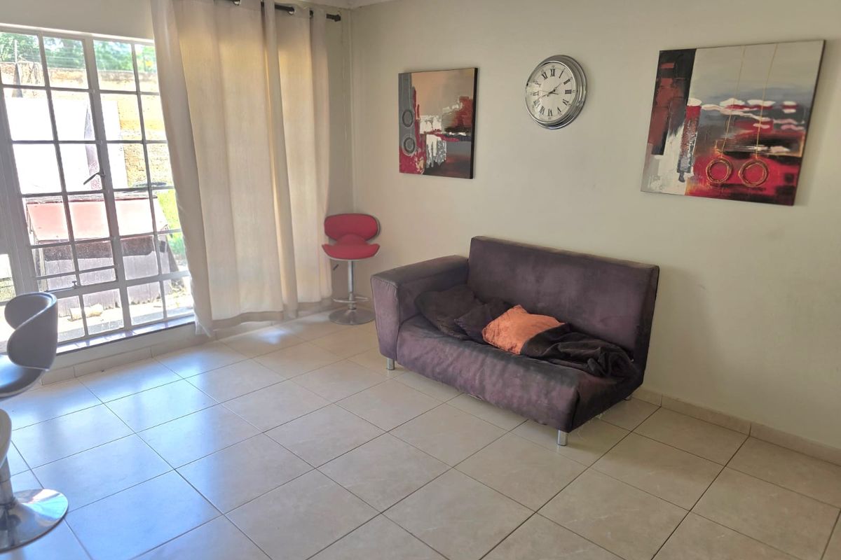 A bright living area featuring neutral tiled flooring and a large sliding glass door providing natural light and access to the exterior.