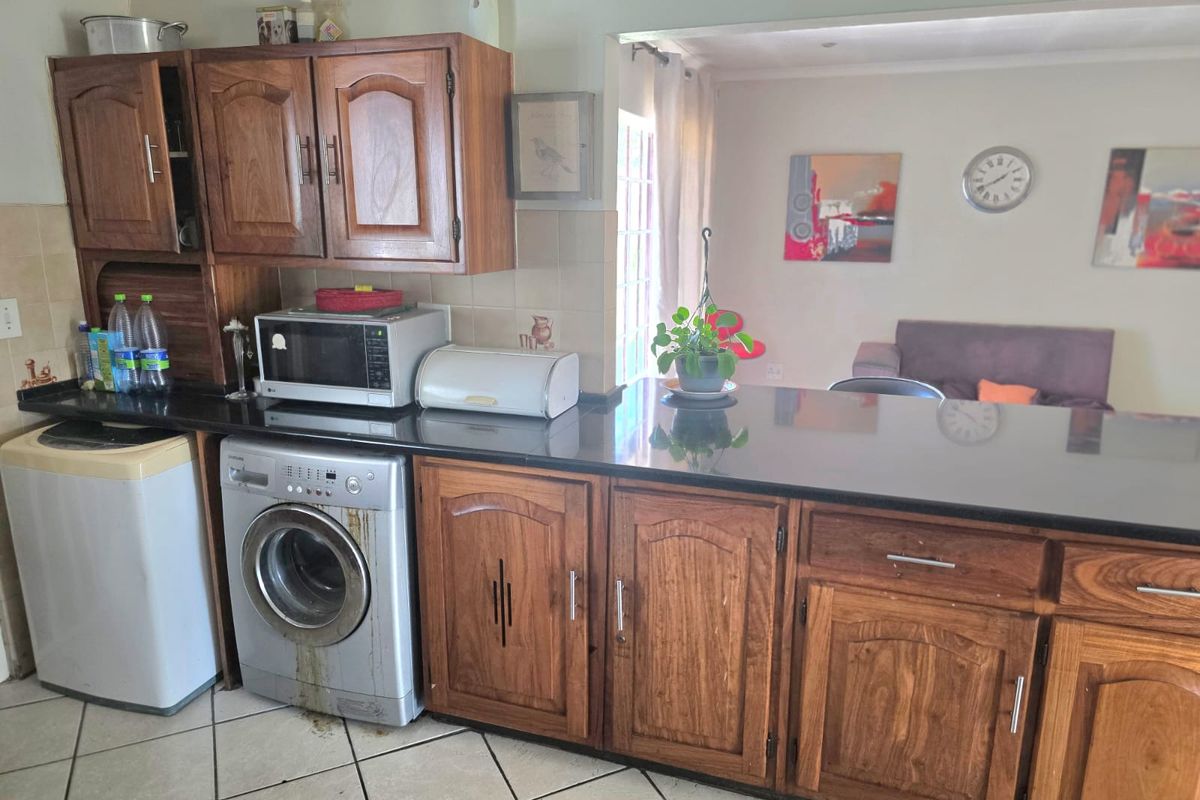 Kitchen featuring wooden cabinetry, granite countertops, and a breakfast bar, with an integrated laundry area and tiled flooring.