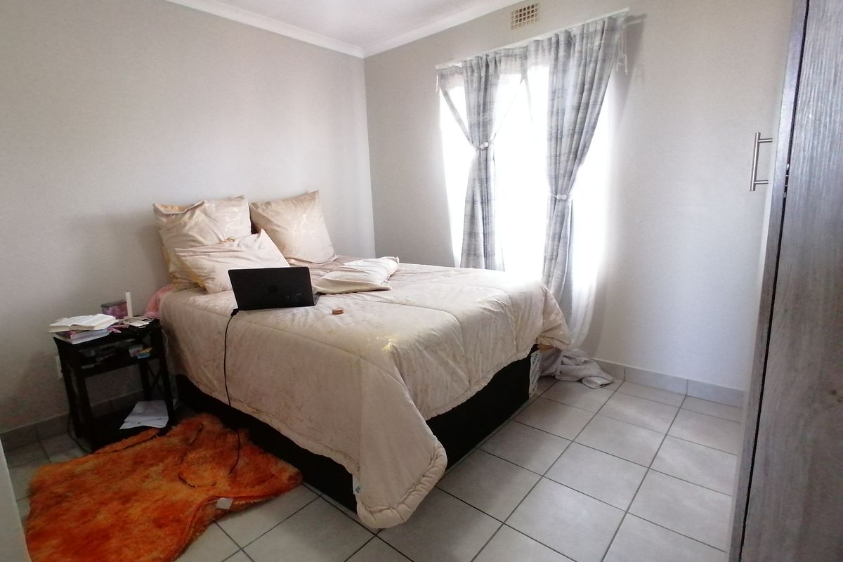 A functional bedroom featuring tiled flooring, built-in cabinetry, and a window allowing natural light into the space.