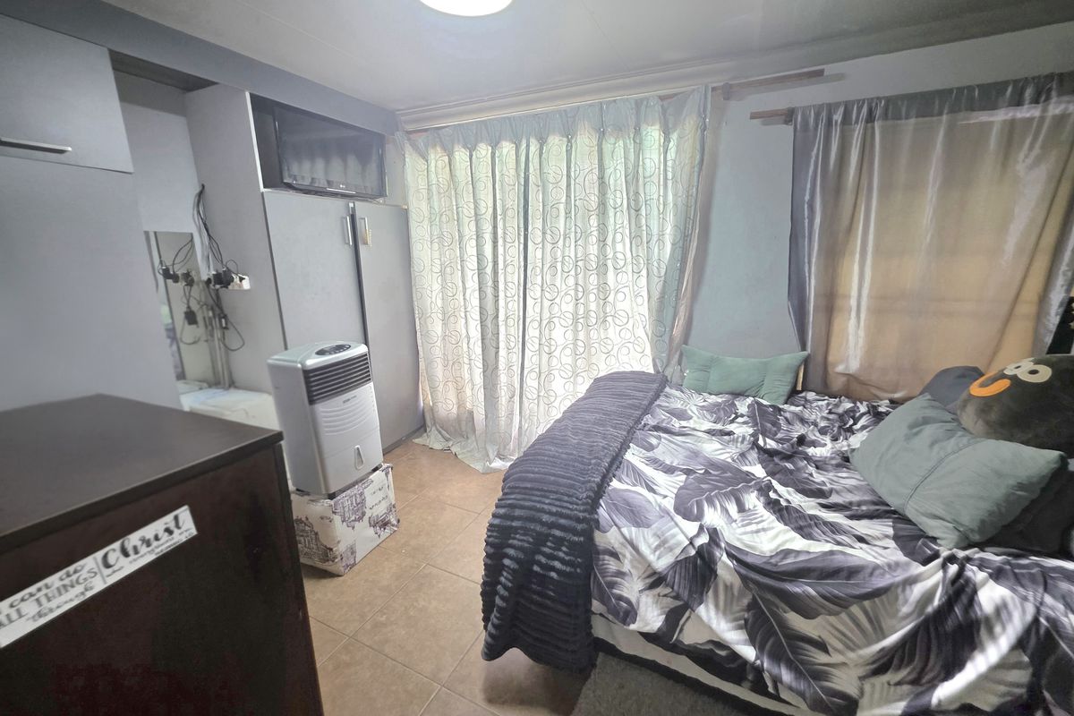 A bedroom featuring tiled flooring and built-in cupboards, requiring cosmetic updates to improve the overall finish and presentation.
