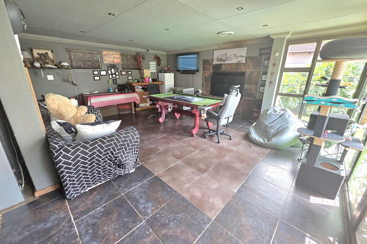 Spacious living area featuring large format floor tiles, recessed ceiling lighting, and a built-in fireplace with direct access to the garden through sliding doors.