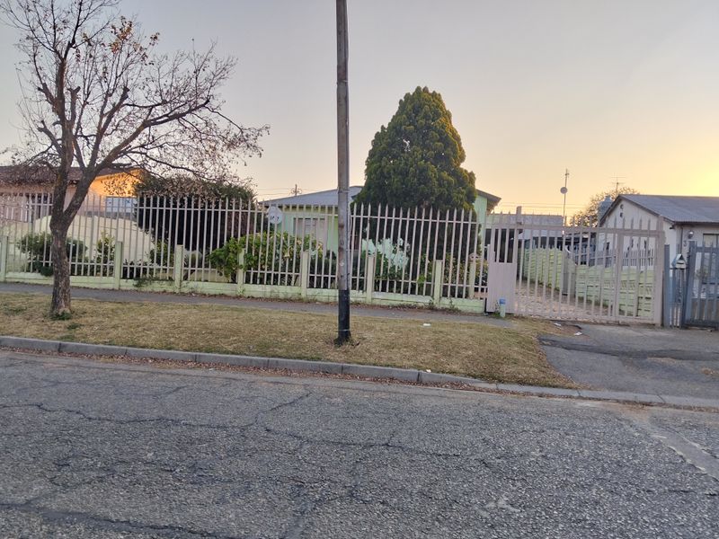 Street view of the property showing the front perimeter fencing, gated driveway entrance, and surrounding residential exterior.