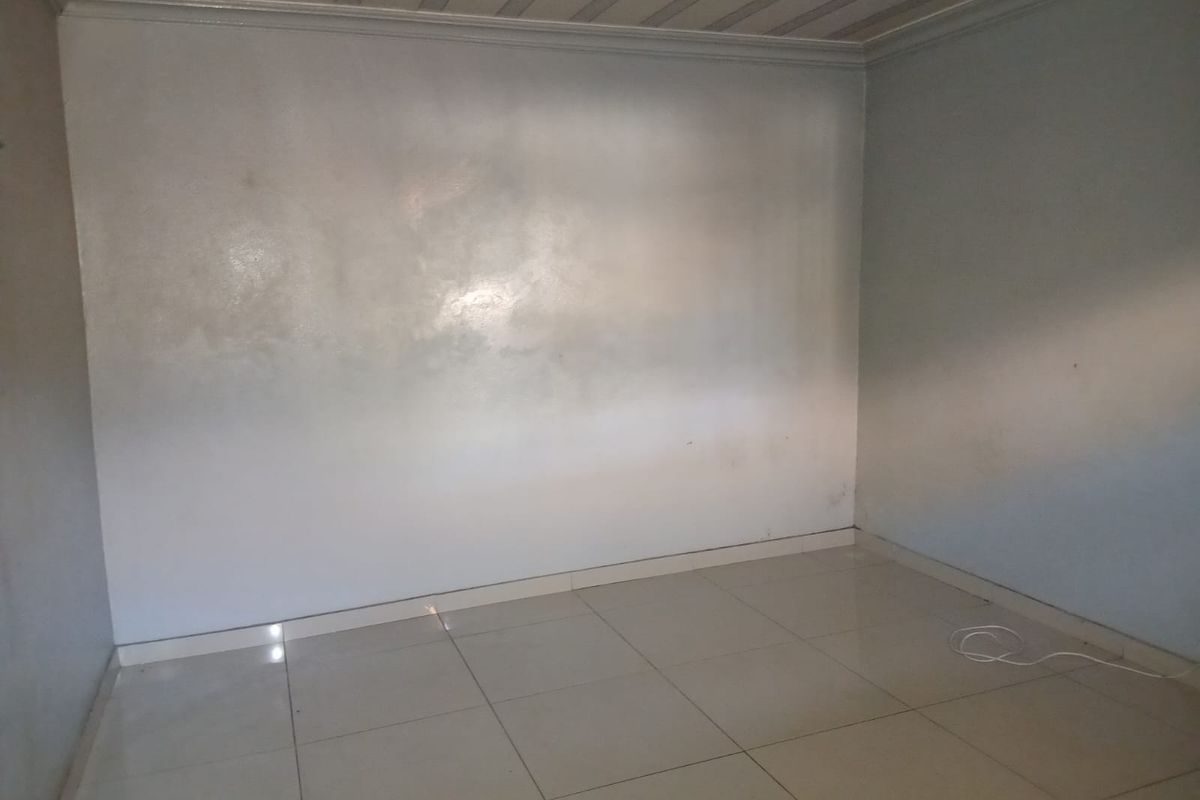 An empty, neutral-toned room featuring tiled flooring and a simple ceiling finish, providing a blank canvas for interior design.