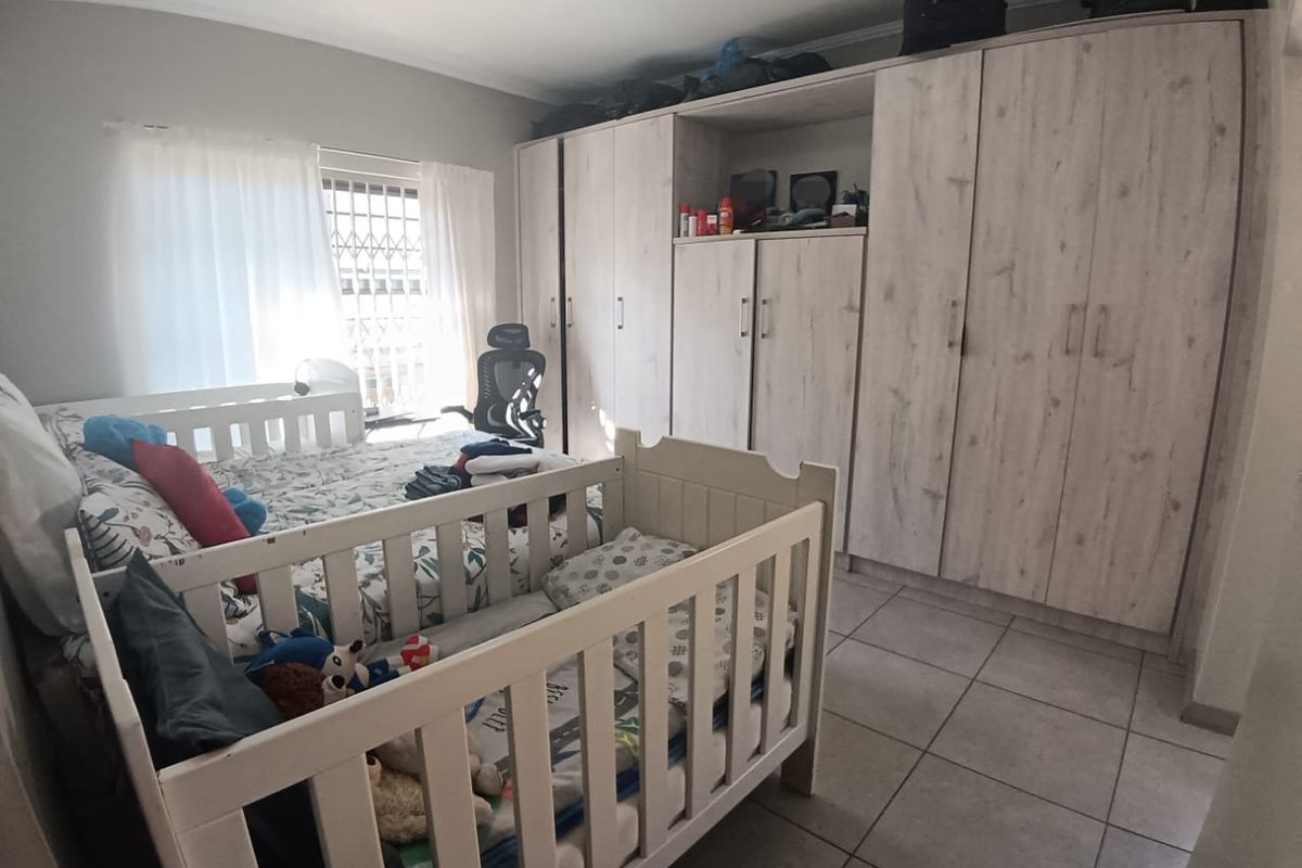 A bedroom featuring built-in light wood-grain cabinetry and tiled flooring, providing ample storage space.