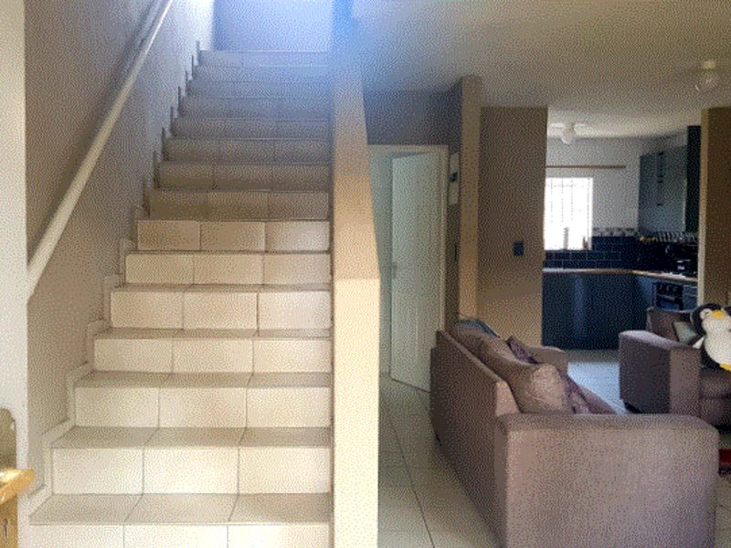Entryway featuring a tiled staircase leading to the upper level, with an open-plan view into the kitchen and living area.
