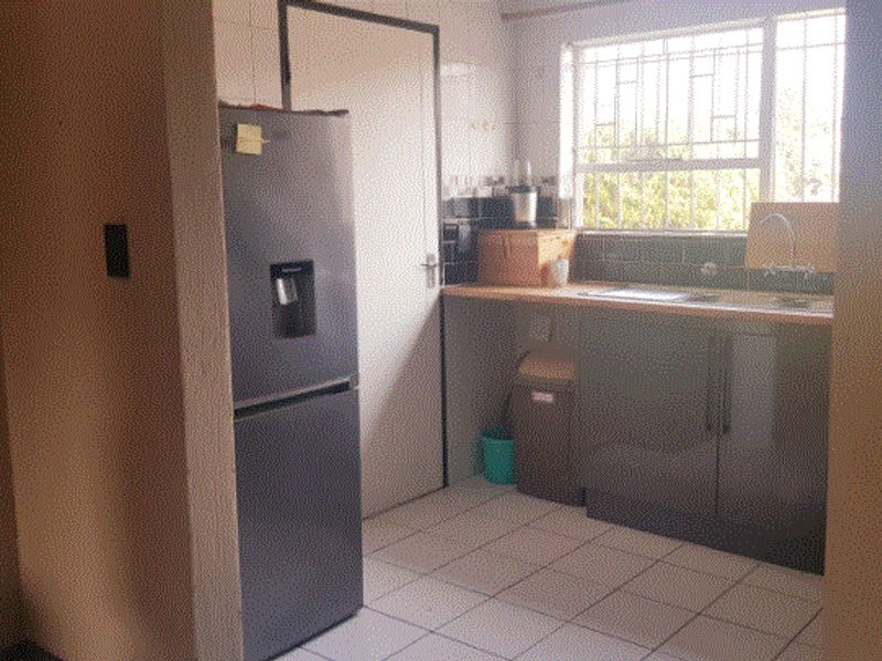 A functional scullery area featuring built-in cabinetry, a stainless steel sink, and tiled flooring, providing additional prep and wash-up space.