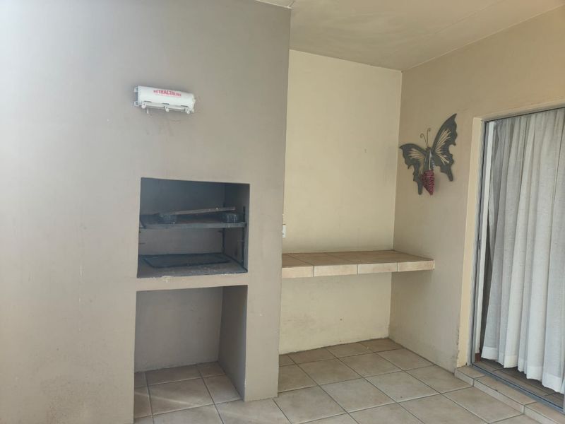 Covered patio area featuring a built-in braai, tiled preparation counter, and direct access to the interior via a sliding door.
