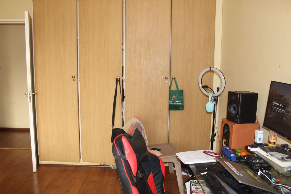 A bedroom featuring built-in wooden cupboards and laminate flooring, providing functional storage space.