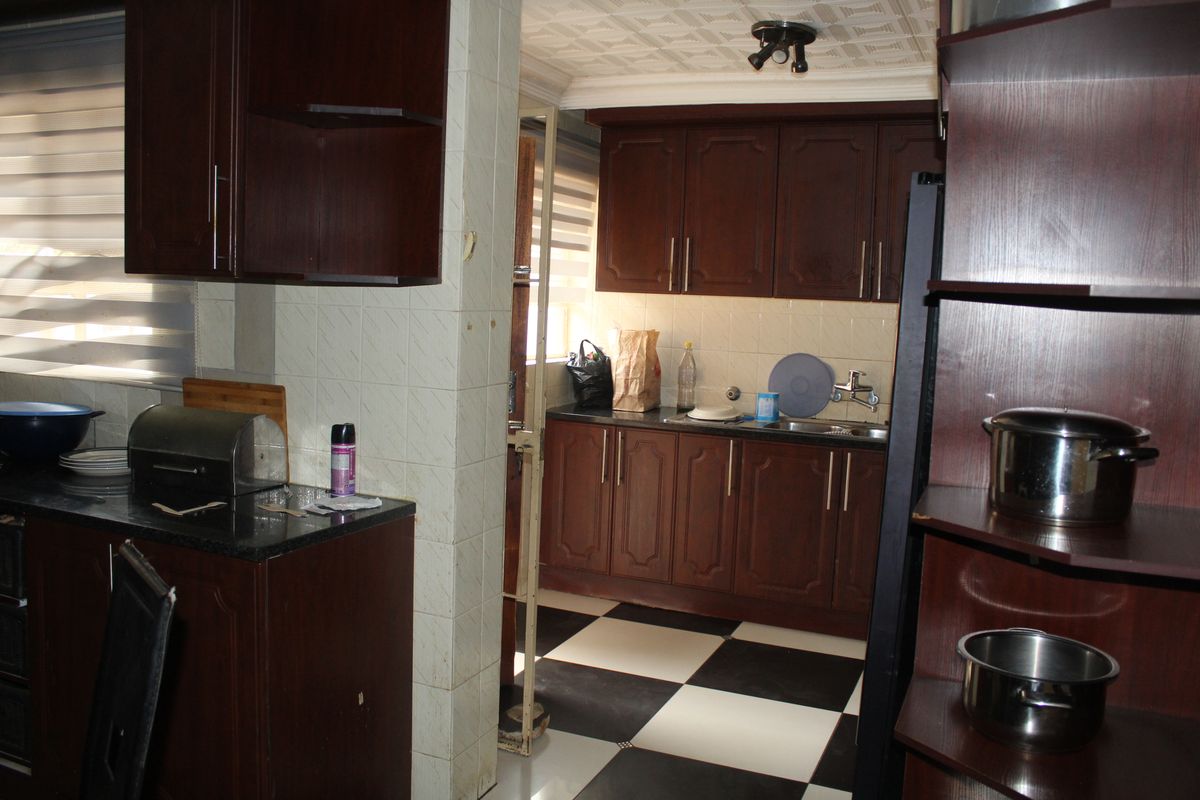A functional kitchen featuring dark wood cabinetry, contrasting black and white checkered floor tiles, and a tiled backsplash with integrated sink and storage.