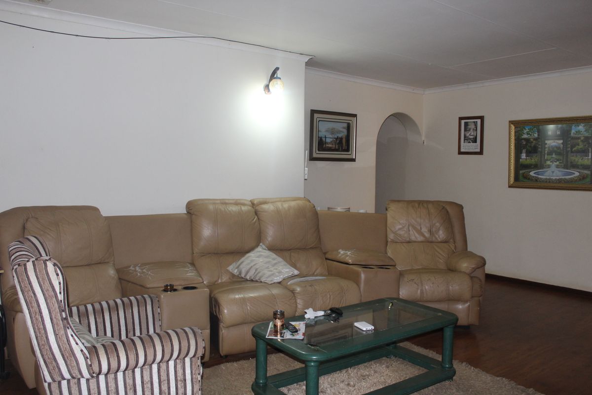 A living room featuring laminate flooring, wall-mounted lighting, and an arched doorway leading to adjacent areas.