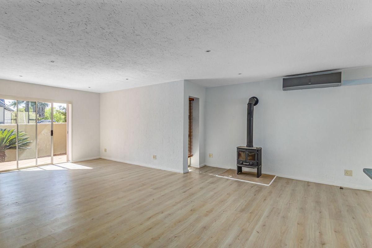 Spacious living area featuring light wood-look flooring, a freestanding wood-burning fireplace, and sliding glass doors providing access to the outdoor patio.