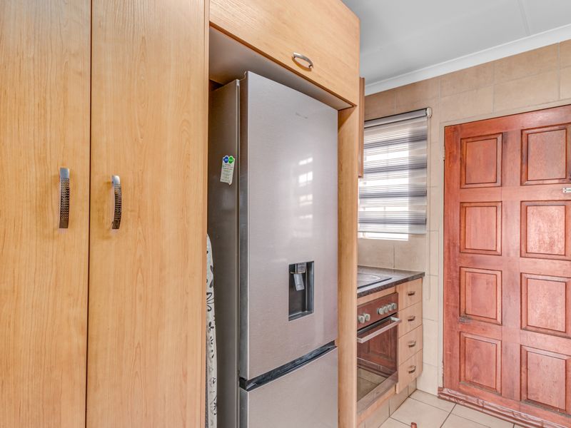 A functional kitchen featuring built-in timber cabinetry, a built-in oven with hob, tiled splashbacks, and a solid timber door.