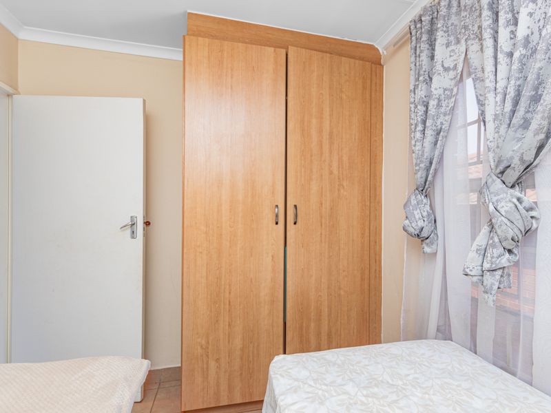 A bedroom featuring a light wood-finish built-in wardrobe and neutral wall tones, providing functional storage space.