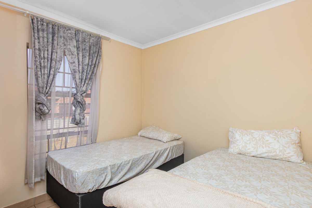 A functional bedroom featuring neutral wall finishes, coving, and a window fitted with security bars.