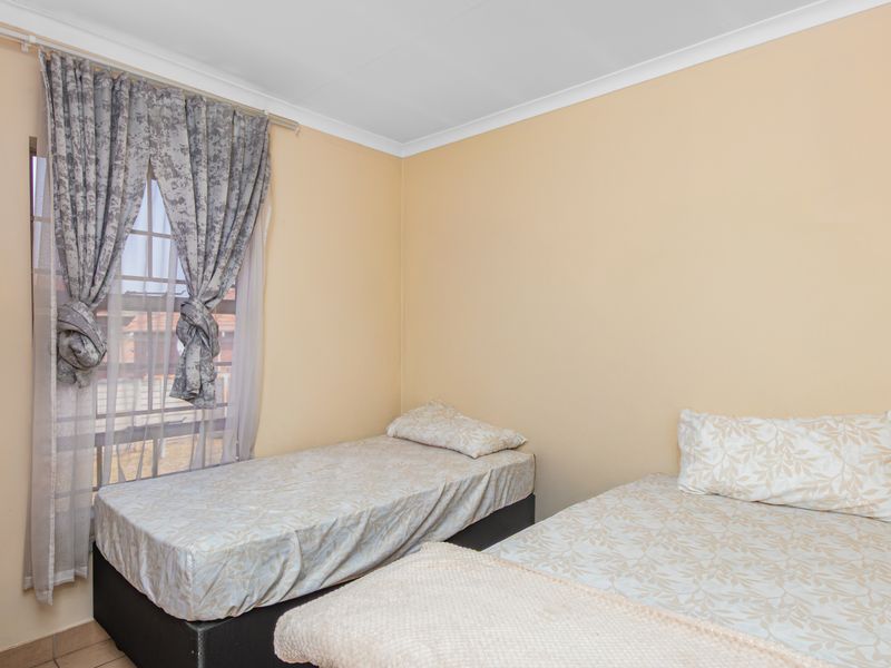 A functional bedroom featuring neutral wall finishes, coving, and a window fitted with security bars.