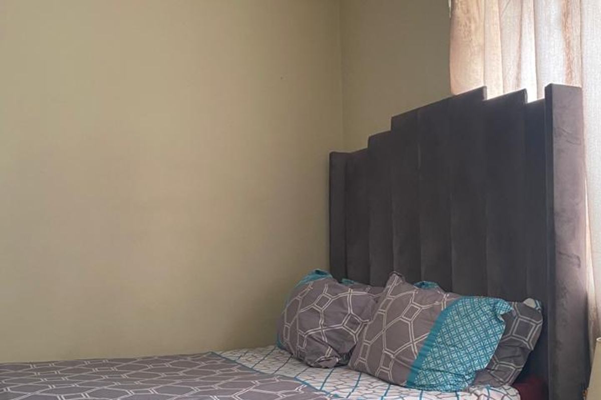 A bedroom featuring a window with curtains and visible signs of ceiling damage requiring maintenance.