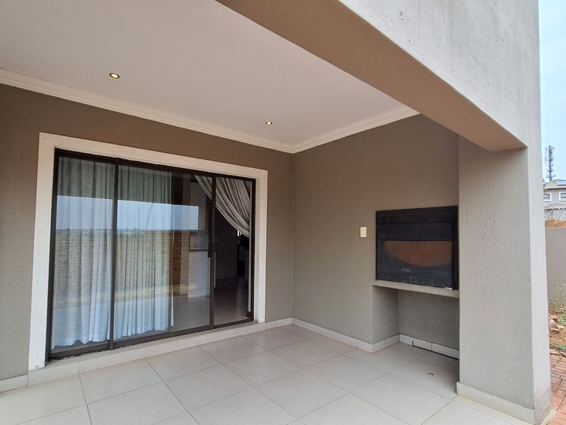 A covered patio featuring tiled flooring, recessed lighting, and a built-in braai, providing a seamless transition to the interior living space.