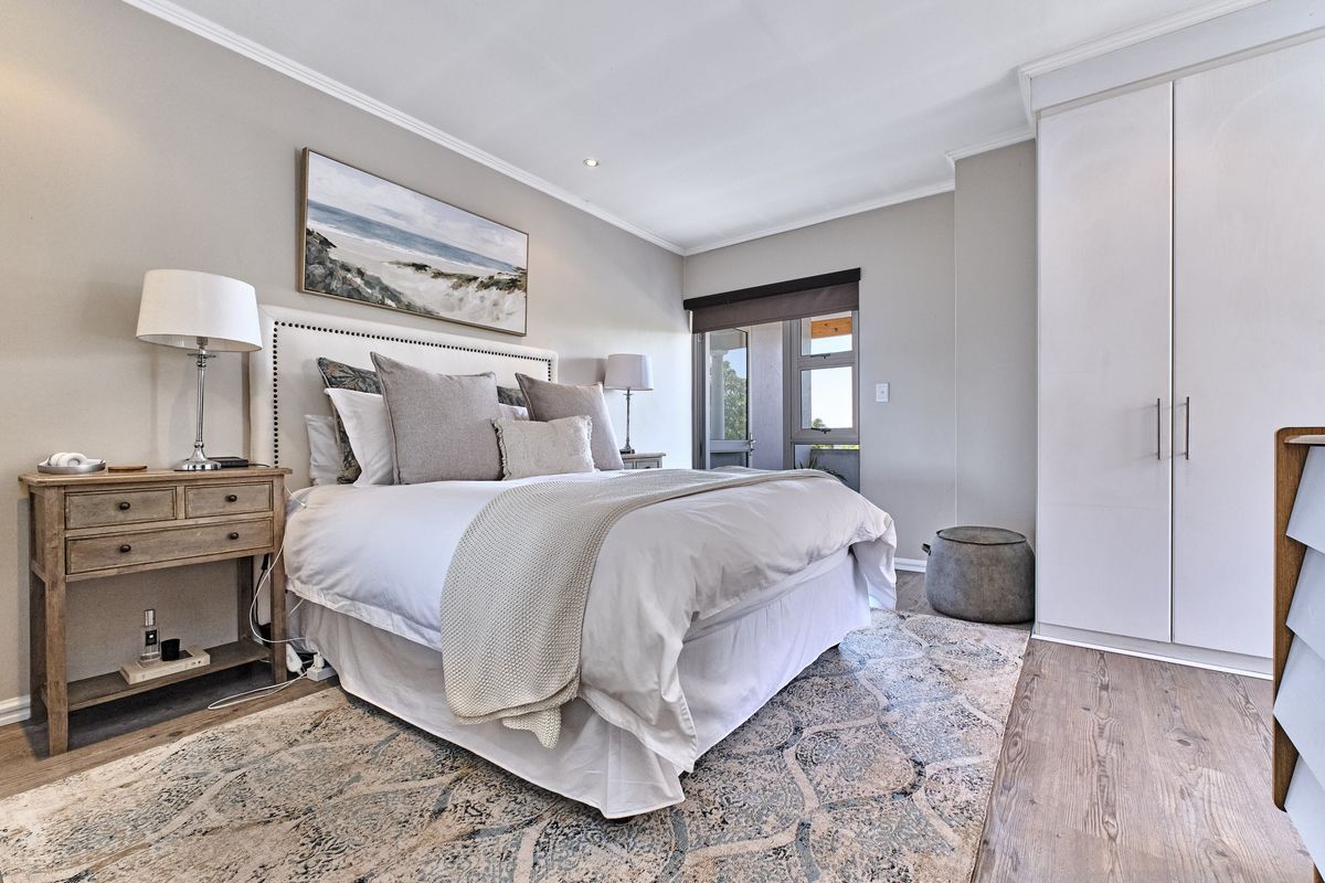 A well-maintained bedroom featuring built-in wardrobes, neutral wall finishes, and direct access to a private balcony.
